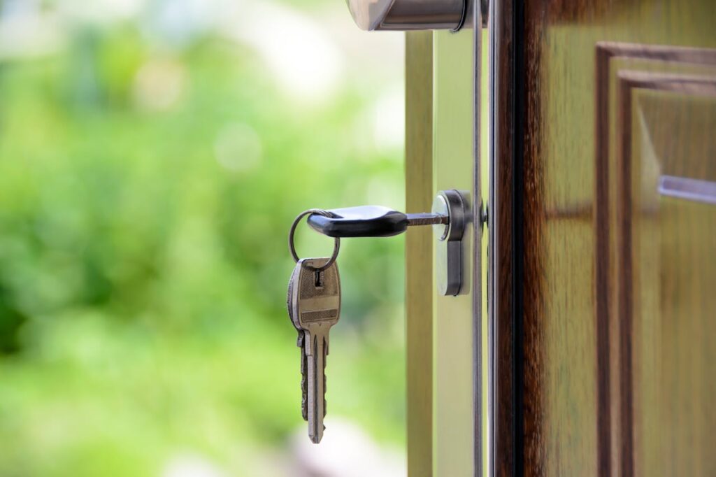 Chiave inserita in una serratura di una porta con sfondo sfocato di un giardino verde